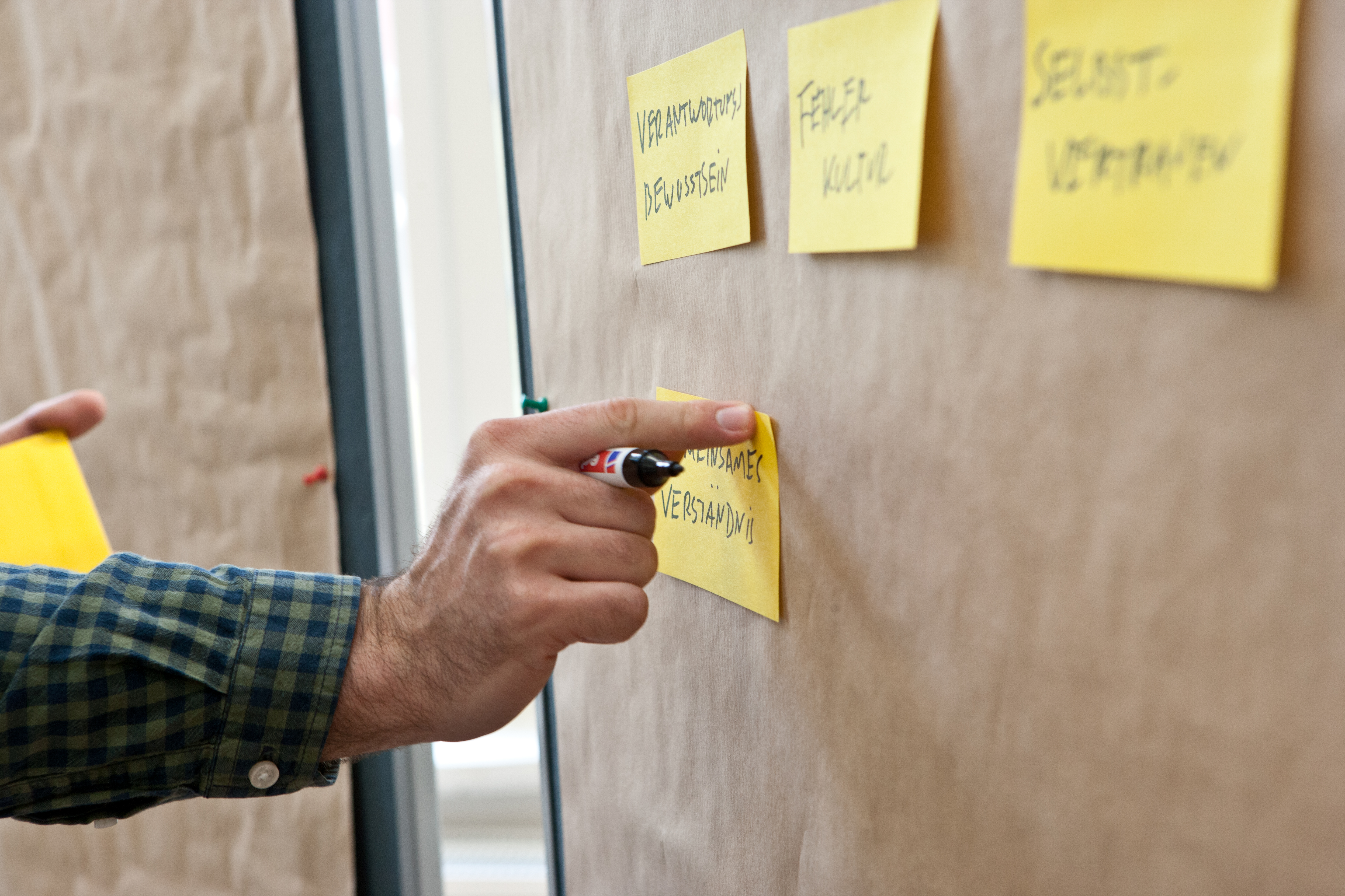 Nahaufnahme: 3 Post-its auf einer Metaplanwand