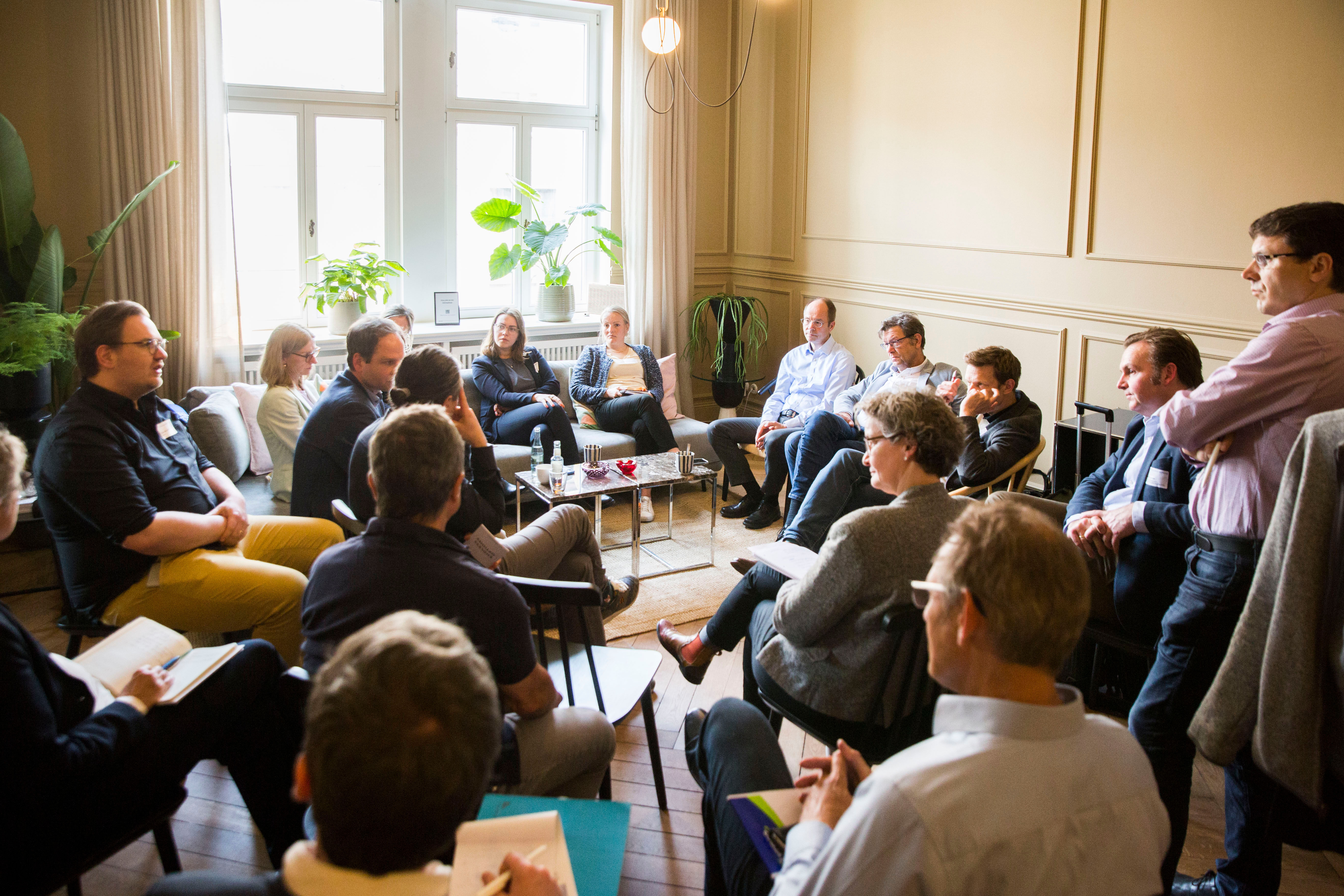 ca. 18 Teilnehmende am Workshop der Denkfabrik am 5.05.24 sitzen zusammen in einem Raum und diskutieren